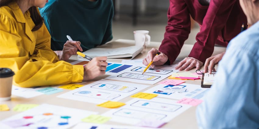Close up ux developer and ui designer brainstorming about mobile app interface wireframe design on table with customer breif and color code at modern office.Creative digital development