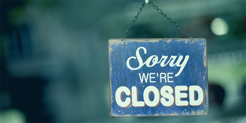 Blue closed sign in the window of a shop displaying the message "Sorry we are closed"