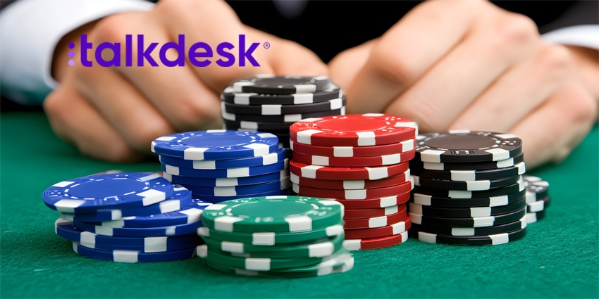 A close-up of stacks of poker chips on a green felt table, with a player's hands in the background.