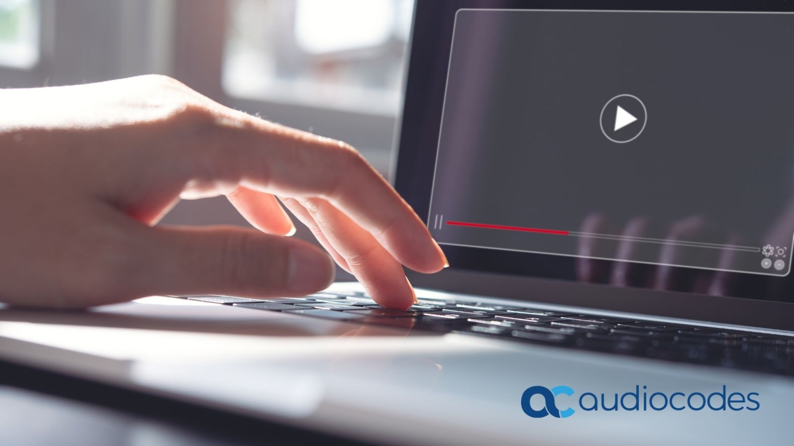 Close-up of a hand at a laptop keyboard about to play a video interview, branded with the AudioCodes logo