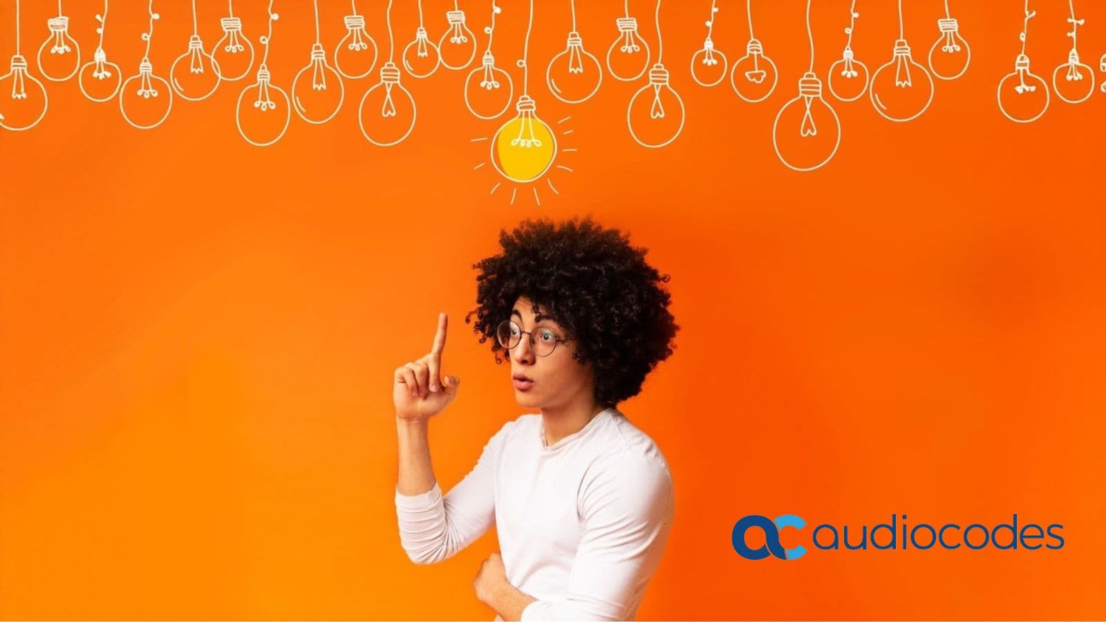 Illustration of a young man with curly hair and glasses pointing upward at a glowing lightbulb idea, against an orange background with hanging bulb outlines and the AudioCodes logo